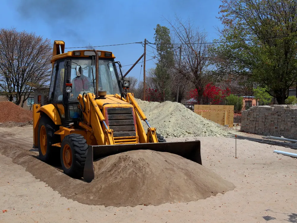 Loader shaping and leveling a dirt pile on a job site