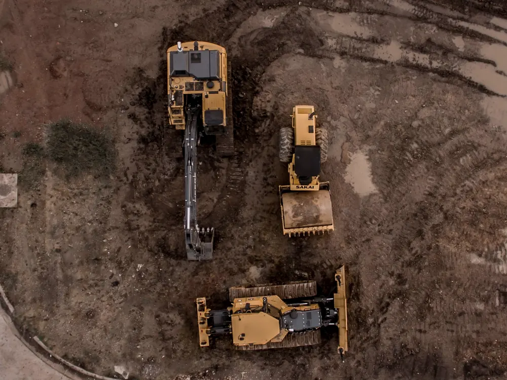 Aerial view of heavy equipment building a compacted dirt pad